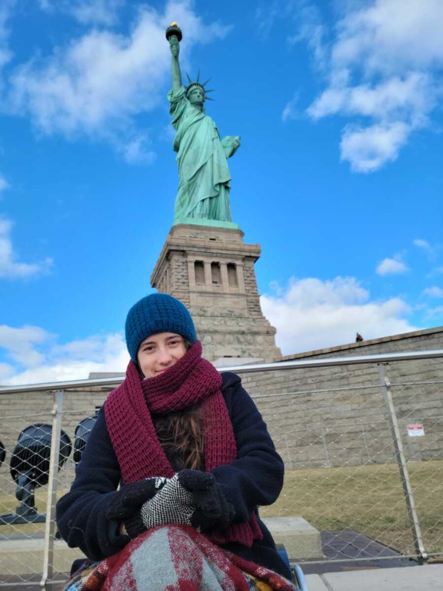 paraplegic woman wearing blue beanie and purple scarf visiting the Eiffel Tower