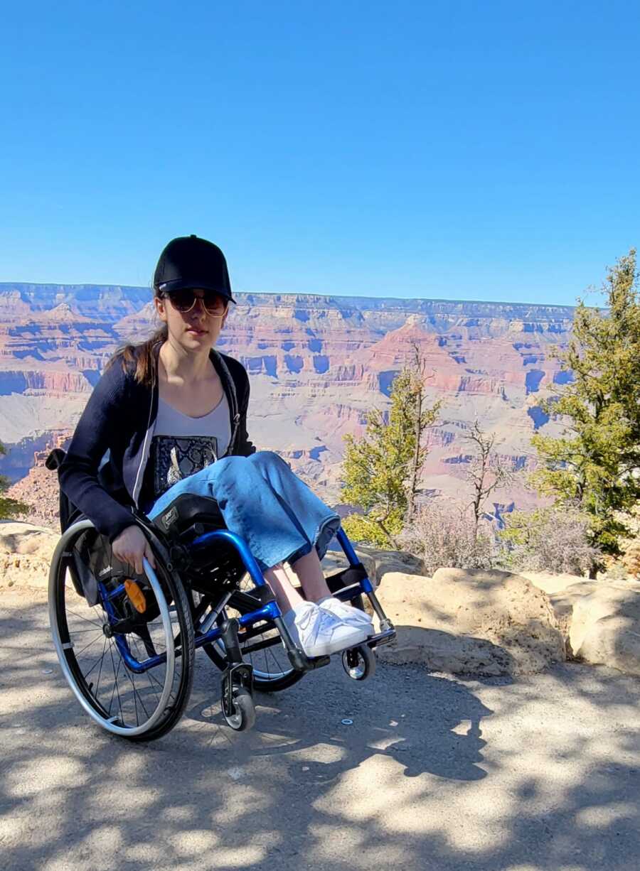 paraplegic woman on hike in wheelchair with canyons behind her