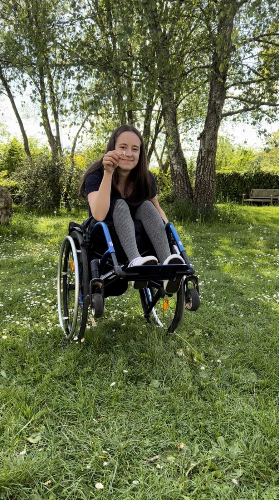 paraplegic woman holding small flower she picked from grass