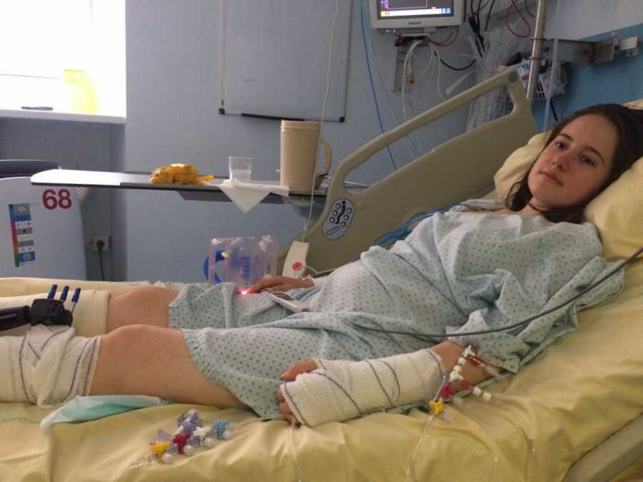 paraplegic woman laying in hospital bed with casts on arms and legs