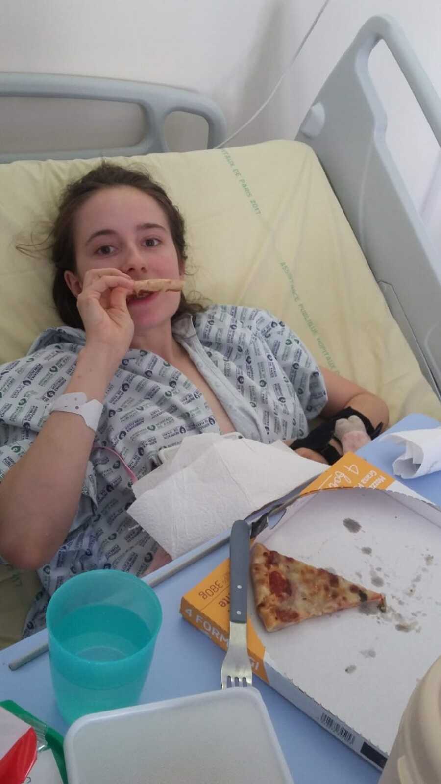 Paraplegic woman laying in hospital bed eating pizza