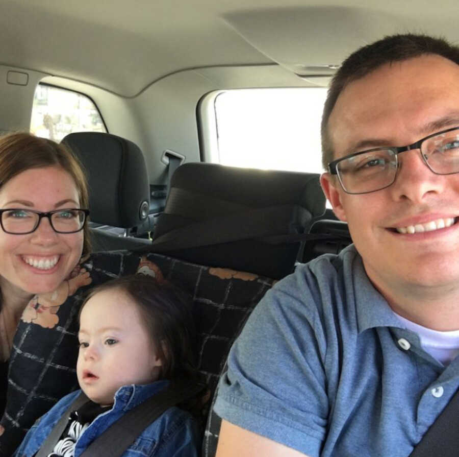 adoptive parents in the backseat with adopted son with Down syndrome