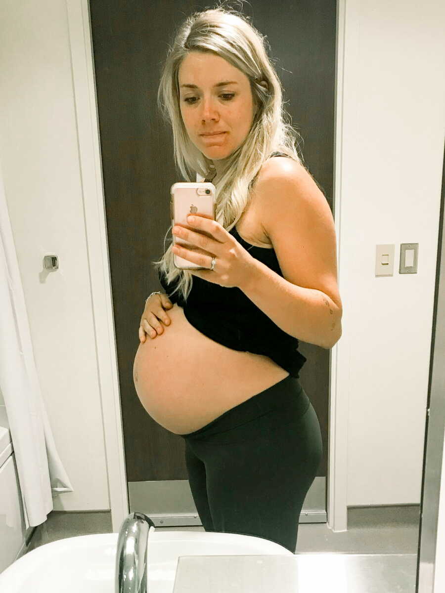 Pregnant mom in the mirror with hand on belly wearing all black