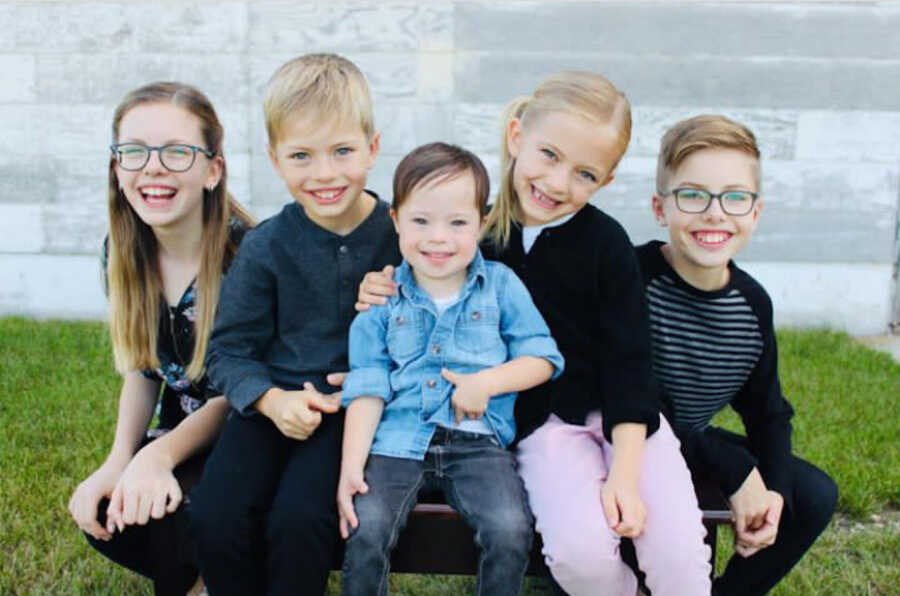 siblings surrounding adopted brother with Down syndrome