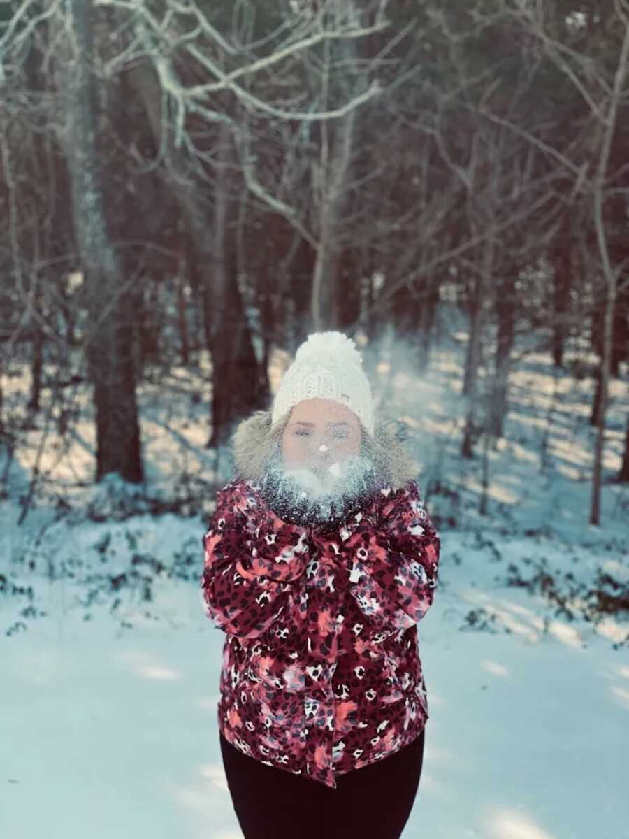 unmarried widow holds snow in hands and blows it towards camera