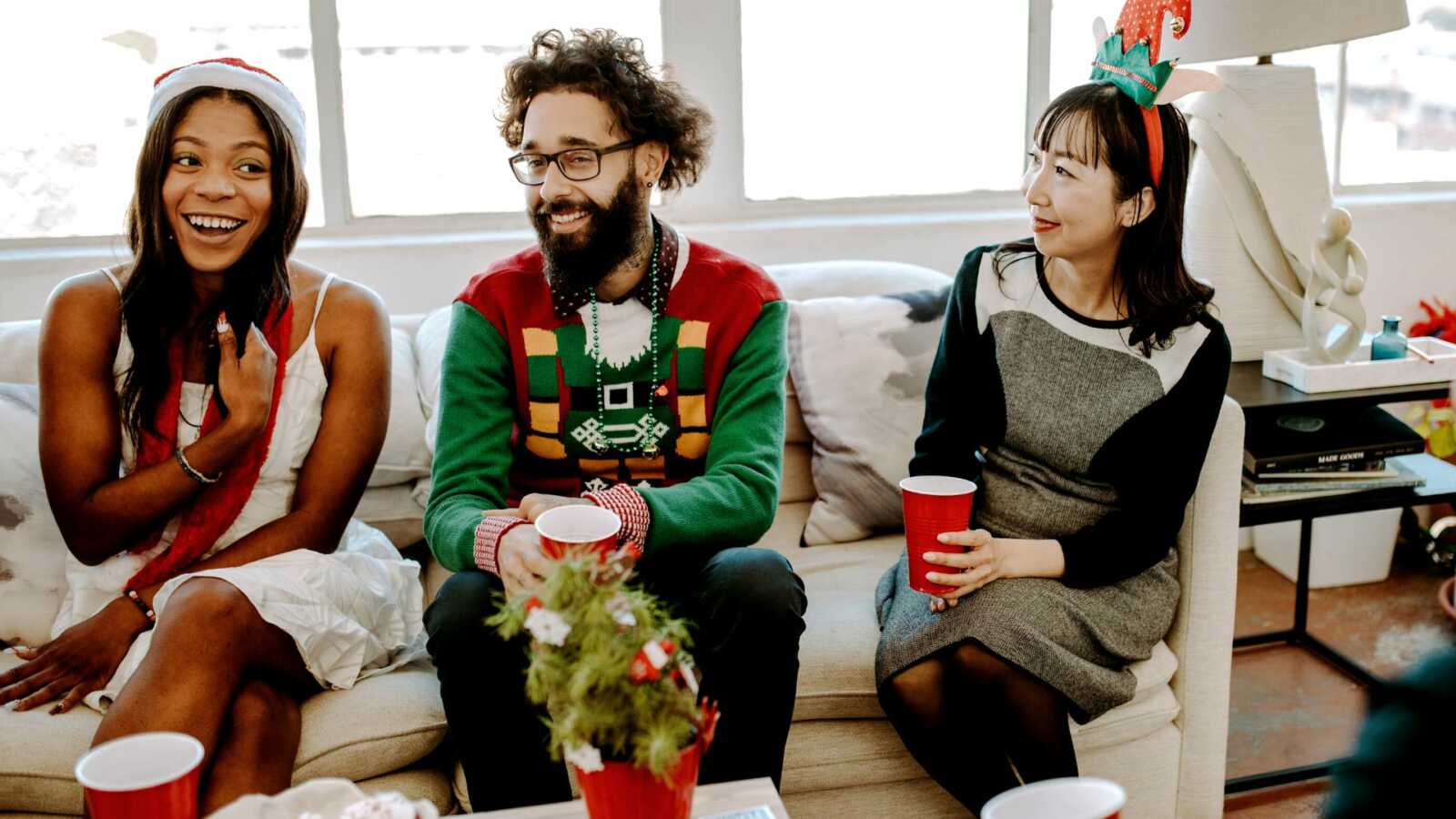 Friend gathered on couch in festive Christmas attire