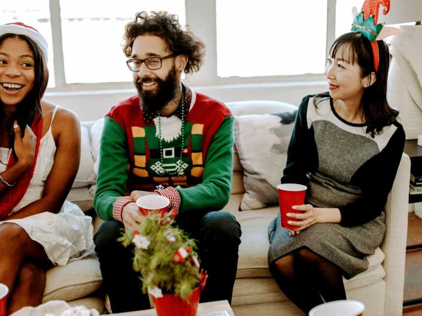 Friend gathered on couch in festive Christmas attire