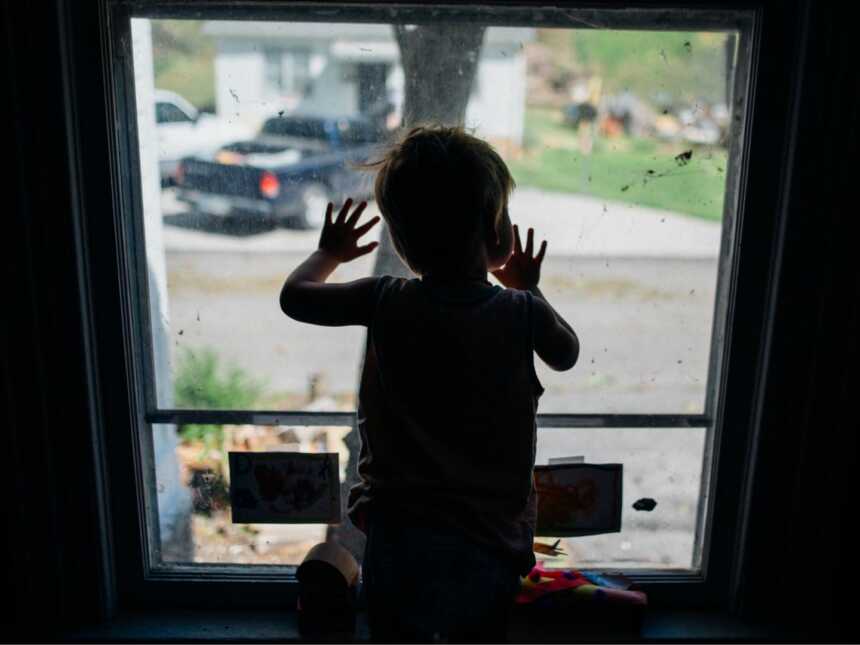 Little boy leaning on glass door