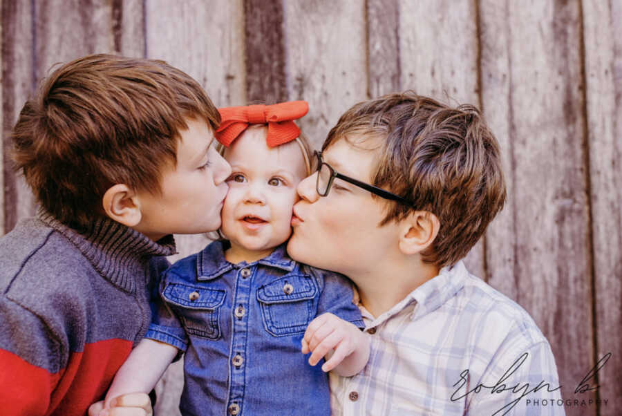 brothers kiss their adoptive sister on her cheeks