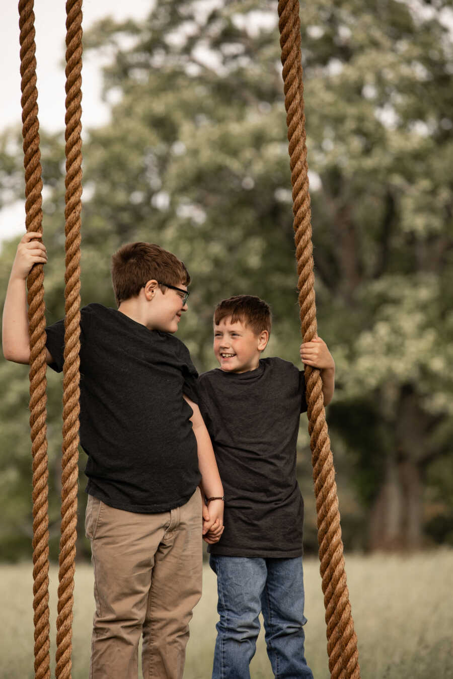 Brothers who were adopted together hold hands and look at each other