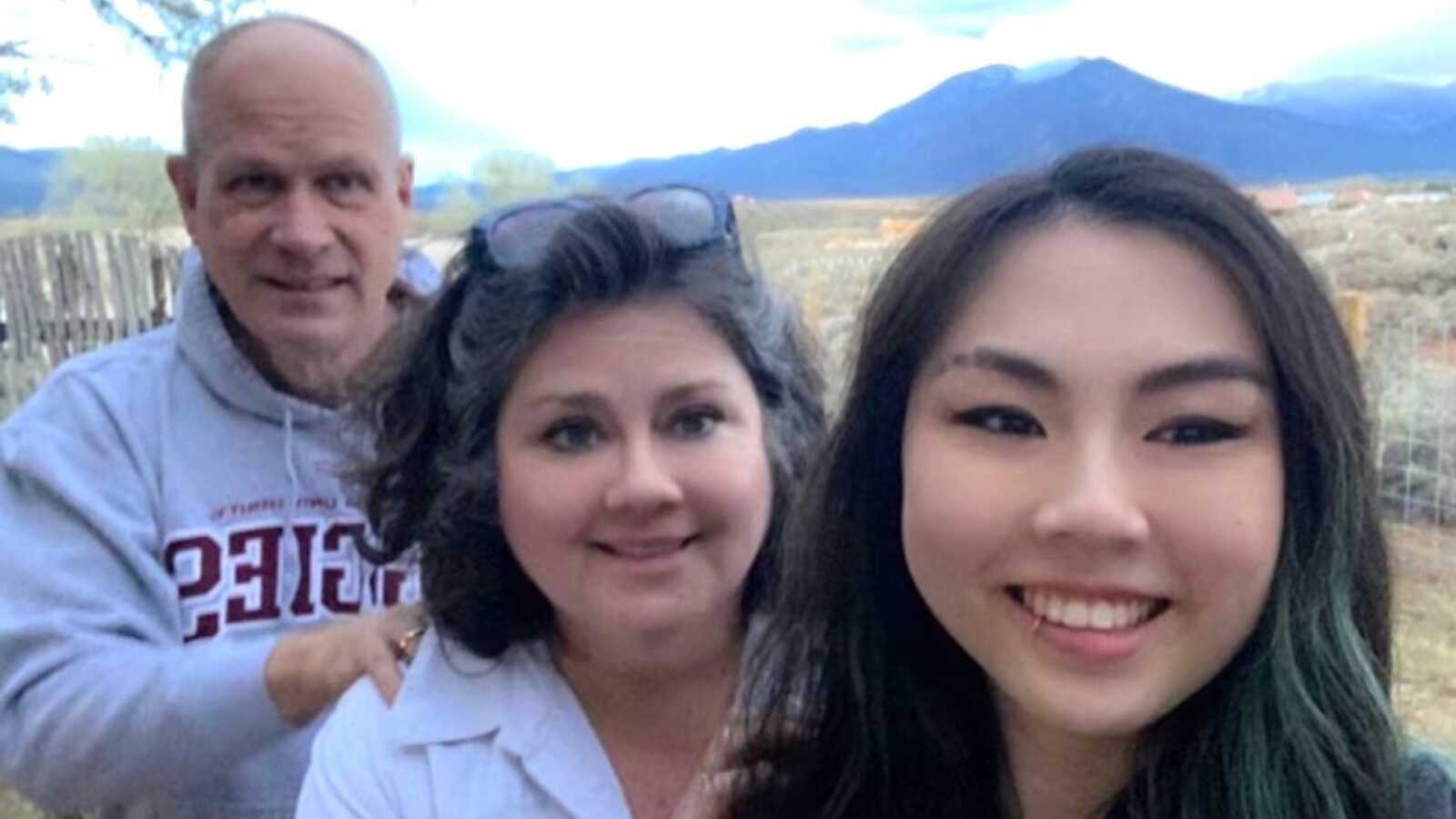 Chinese adoptee takes a selfie in front of mountains with her adoptive parents