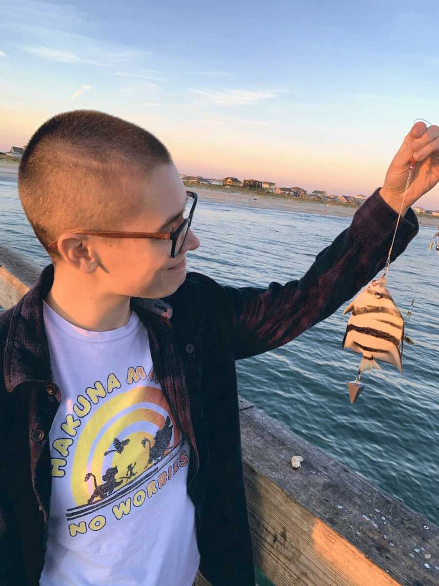 woman with Ehlers-Danlos syndrome holding up tropical fish on fishing line