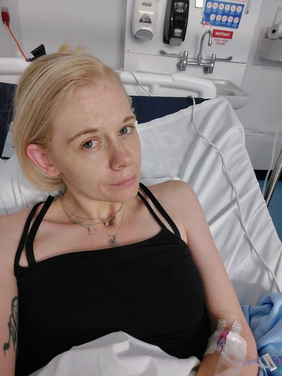 woman with chronic illness sitting in hospital bed takes a selfie