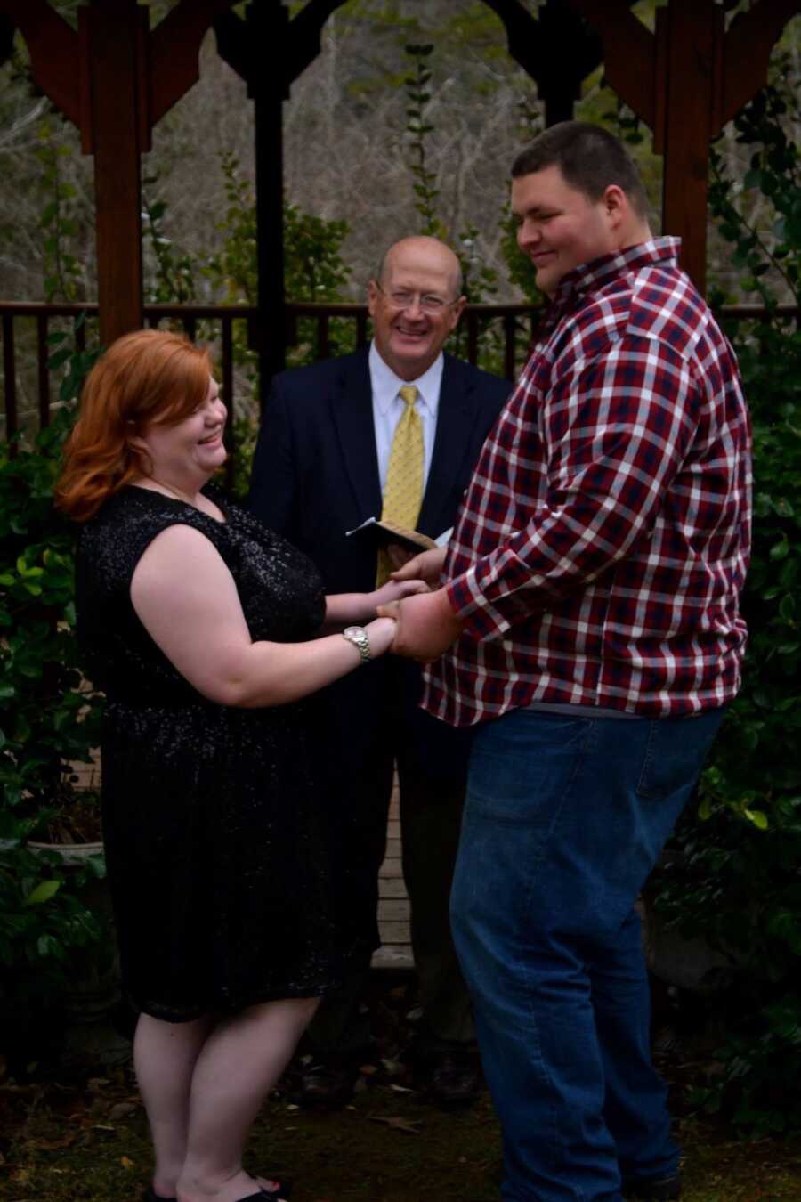 couple stands at the altar holding hands on their wedding day