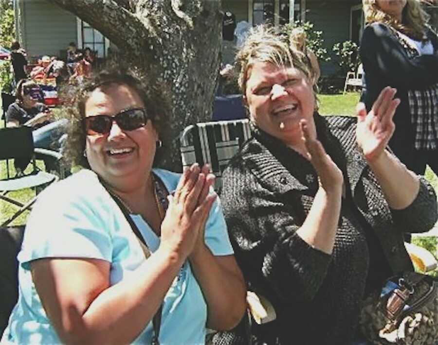 mother and aunt sitting outside at table and clapping