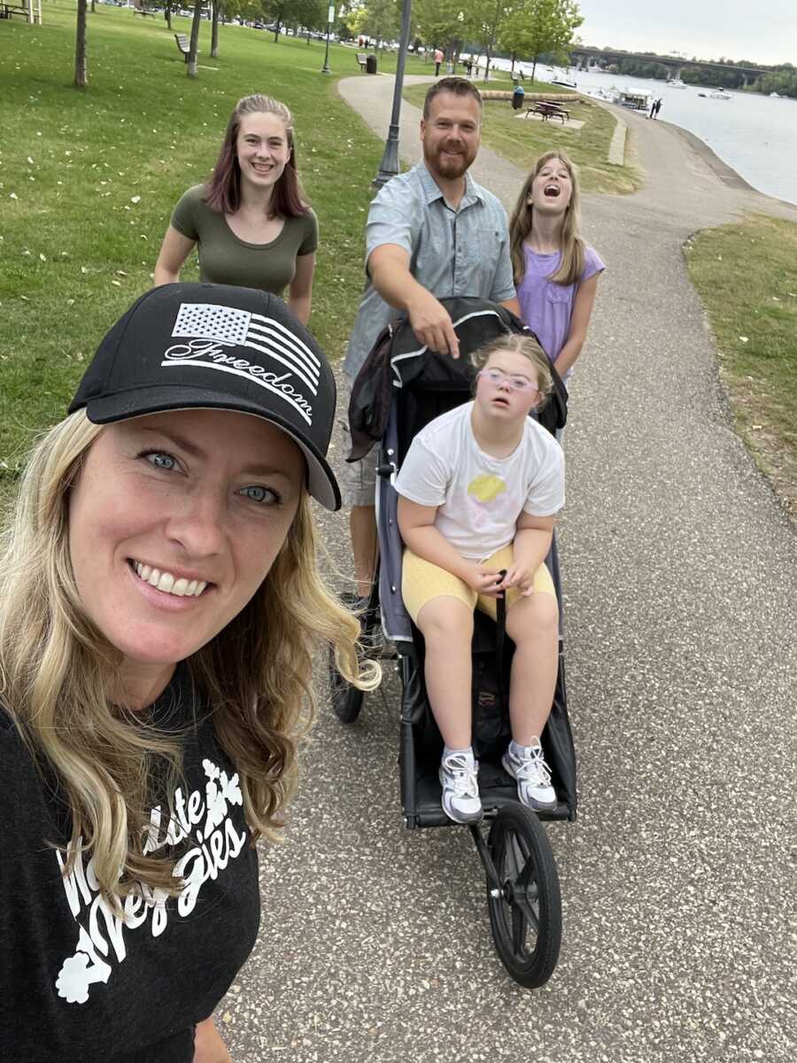 Family of five walk in the park with daughter with special needs in stroller