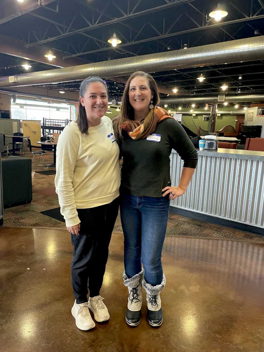 two foster moms stand with arms around each other in a restaurant 