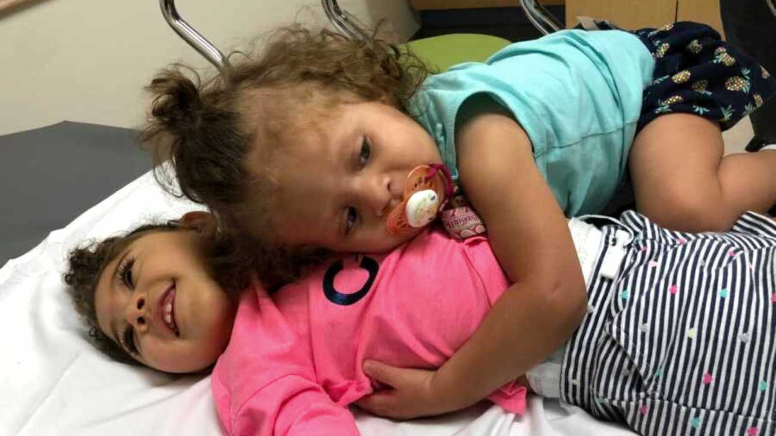 Girl holding special needs sister in hospital bed