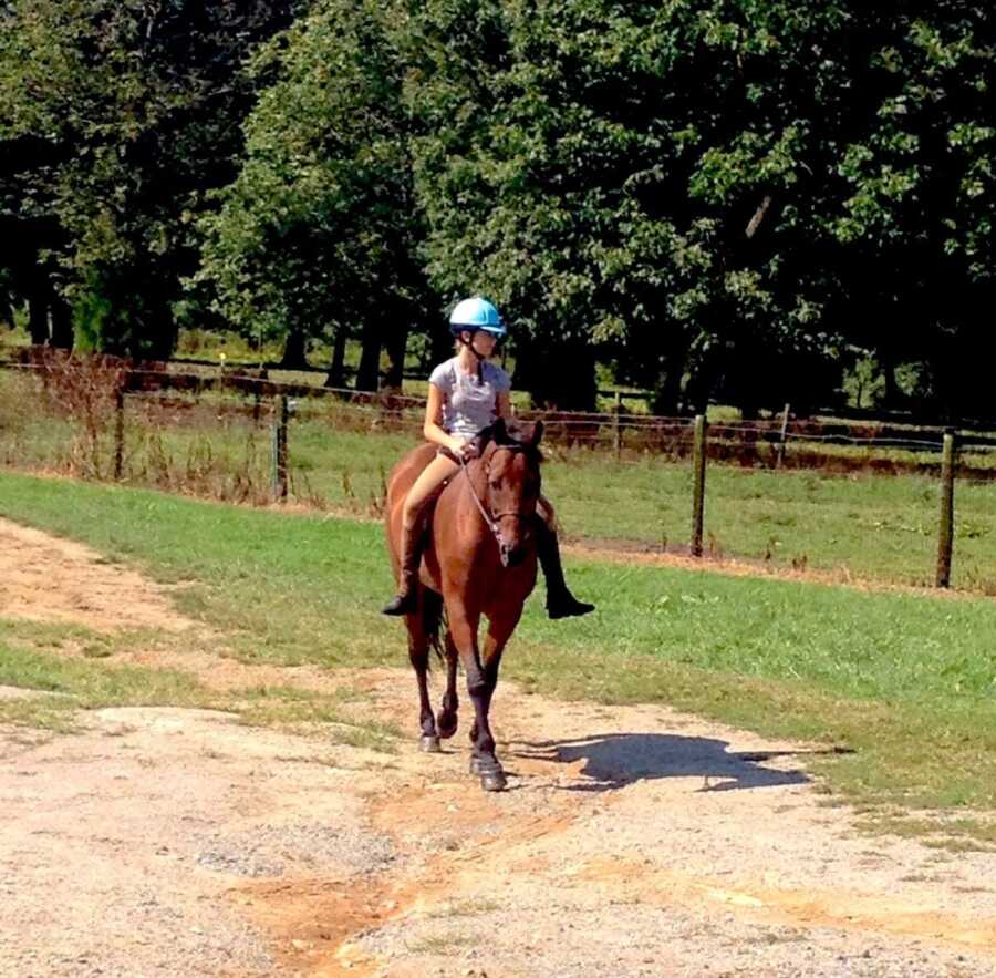 girl horseback riding on a brown horse