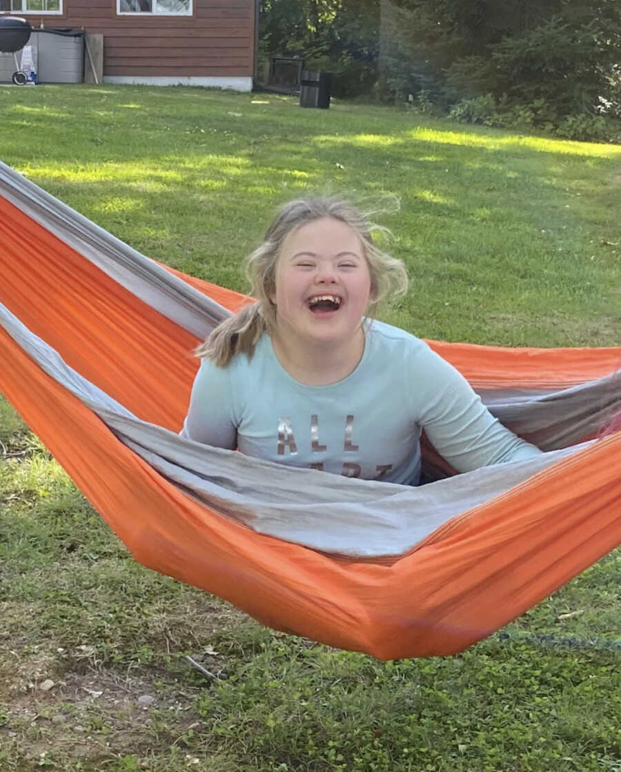 girl with special needs sitting in hammock smiling widely