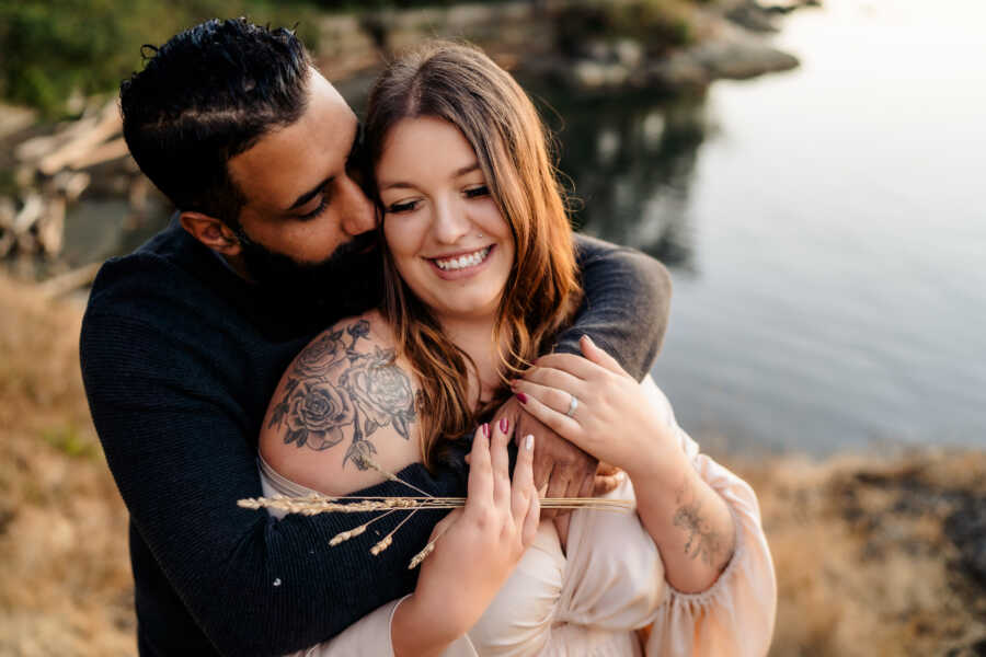 single mom being embraced by her partner who kisses her cheek