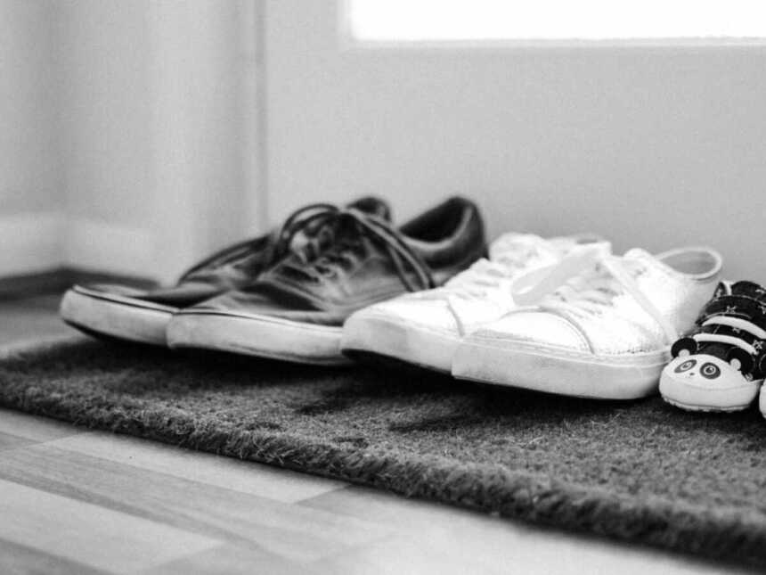 Adult and baby shoes lined up on welcome mat