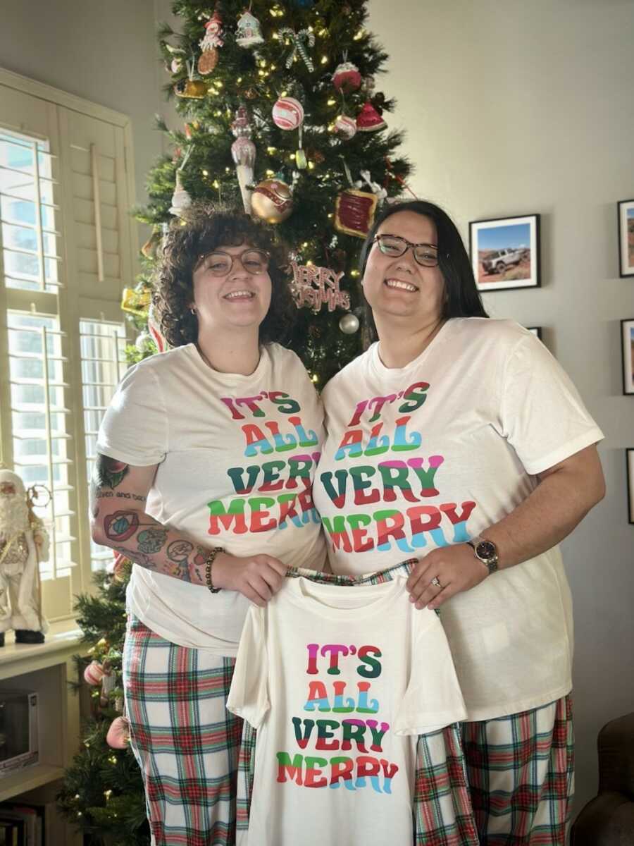 LGBTQ+ prospective adoptive parents in matching pajamas holding up a pair for their daughter