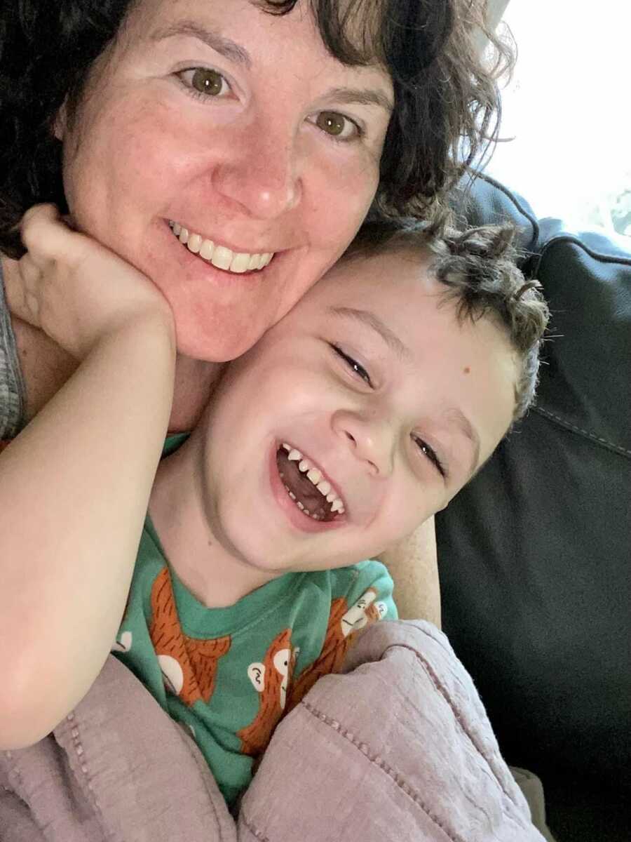 mom and toddler son lying on couch laughing with each other