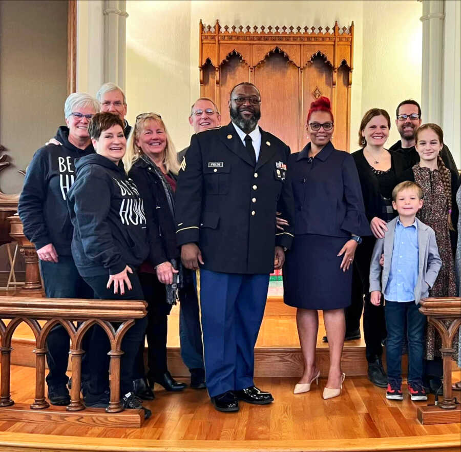 army veteran that is now a pastor wearing dress blues in church surrounded by family friends