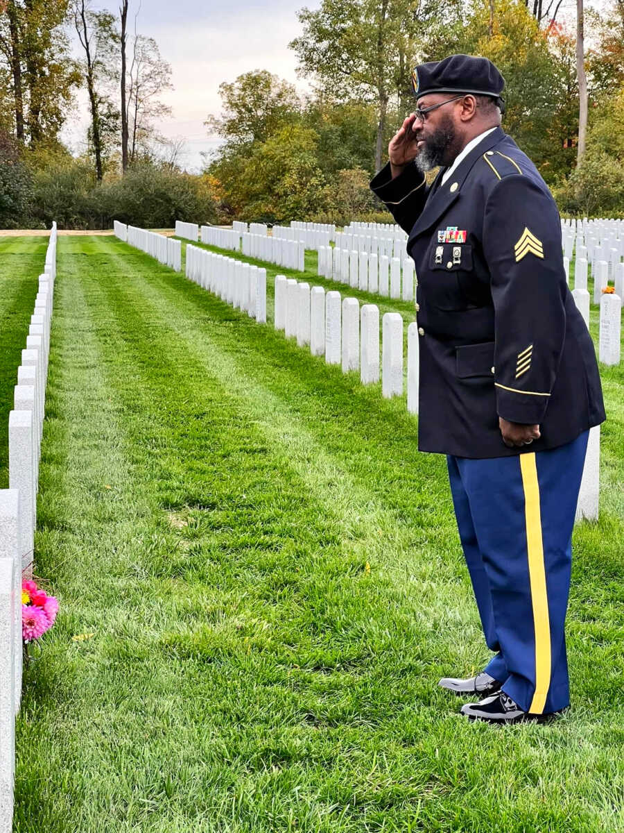 army veteran that is now a pastor in dress blues saluting at memorial grave sight