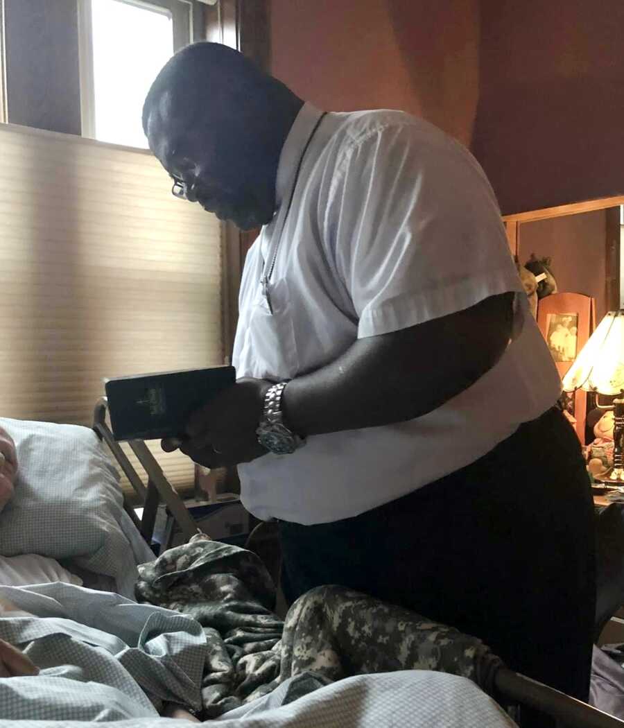 Army veteran that is now a pastor praying over elderly veteran in bed