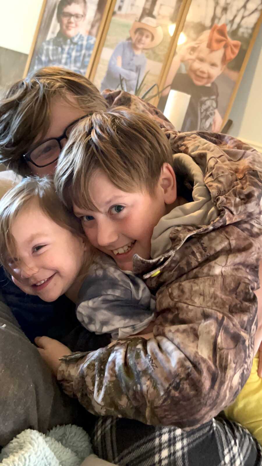 group of three siblings through adoption huddled together, smiling