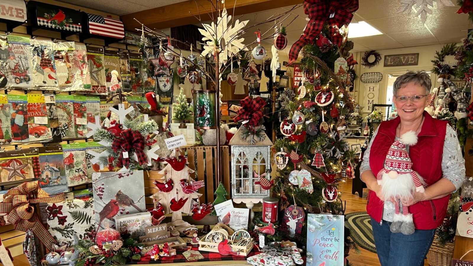 Small business owner in her Christmas decorations shop hiding a mini Santa
