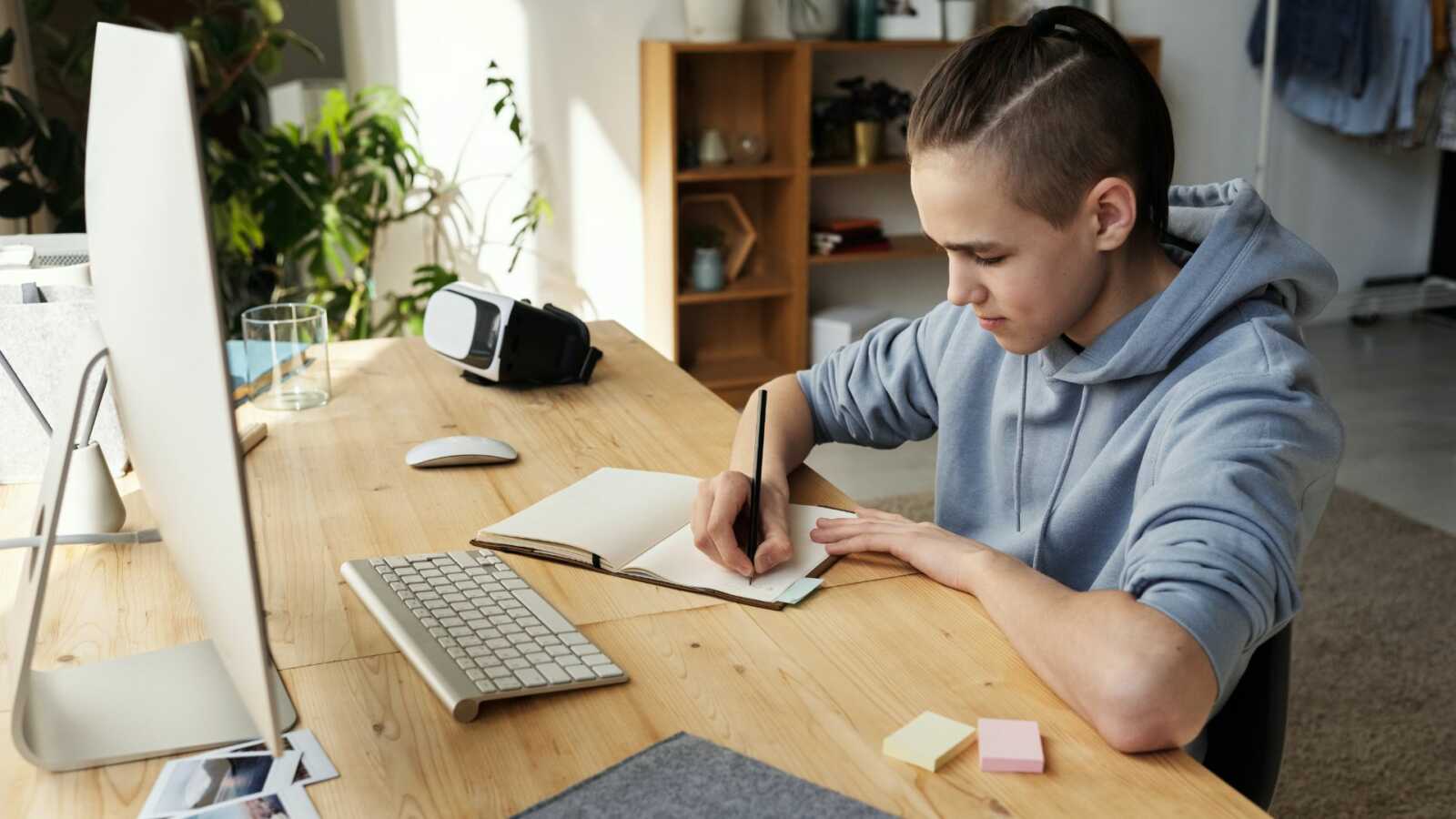 Teen boy in blue hoodie writing in journal