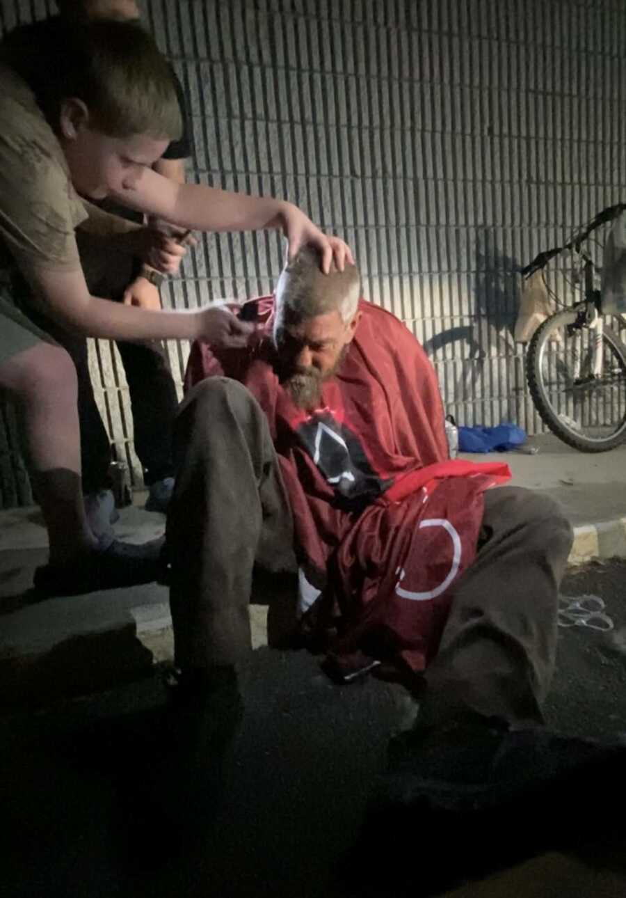Boy cutting homeless man's hair