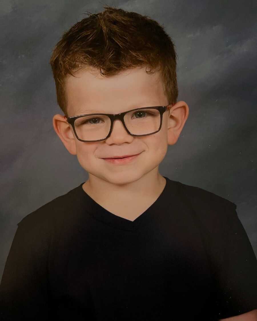 boy with Sanfilippo Syndrome's school photo, wearing glasses and a black shirt