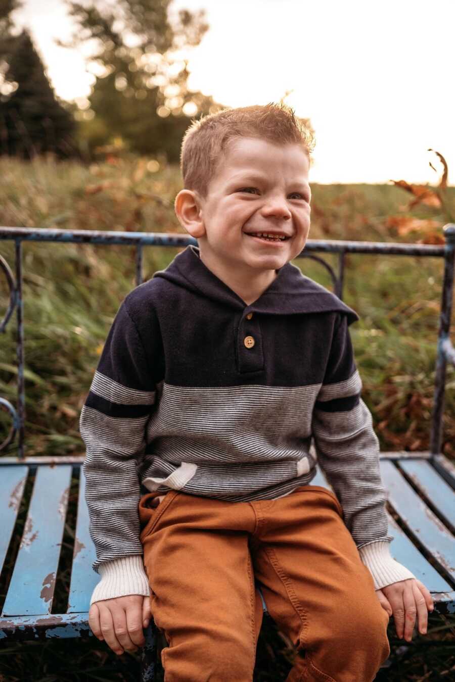 boy with Sanfilippo Syndrome sitting while smiling wide