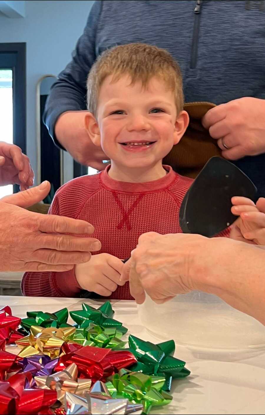 boy with Sanfilippo Syndrome sitting at a table around family with Christmas bows in front of him