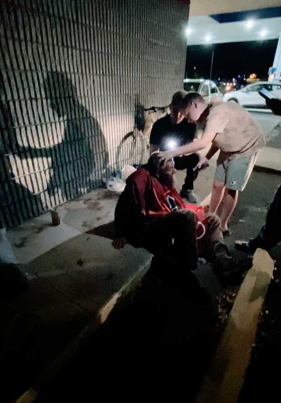 Boy holding homeless man's head