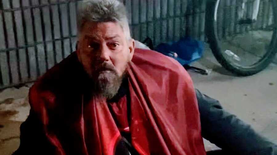 Homeless man wearing red barber cape