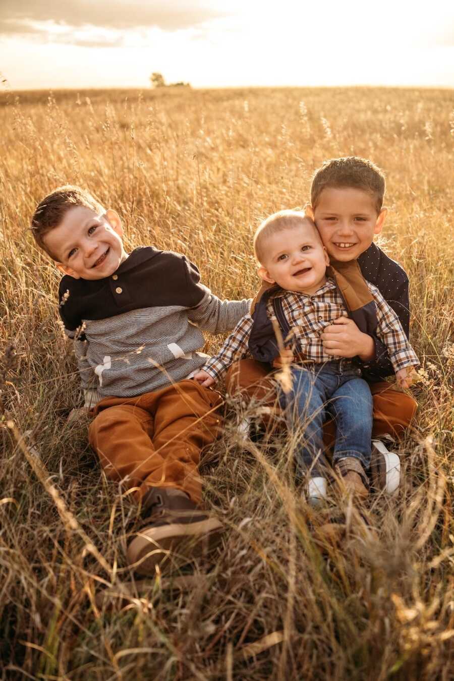 three brothers sitting together in an open field