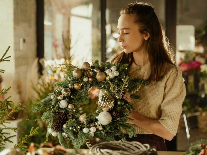 Woman in brown sweating holding Christmas wreath