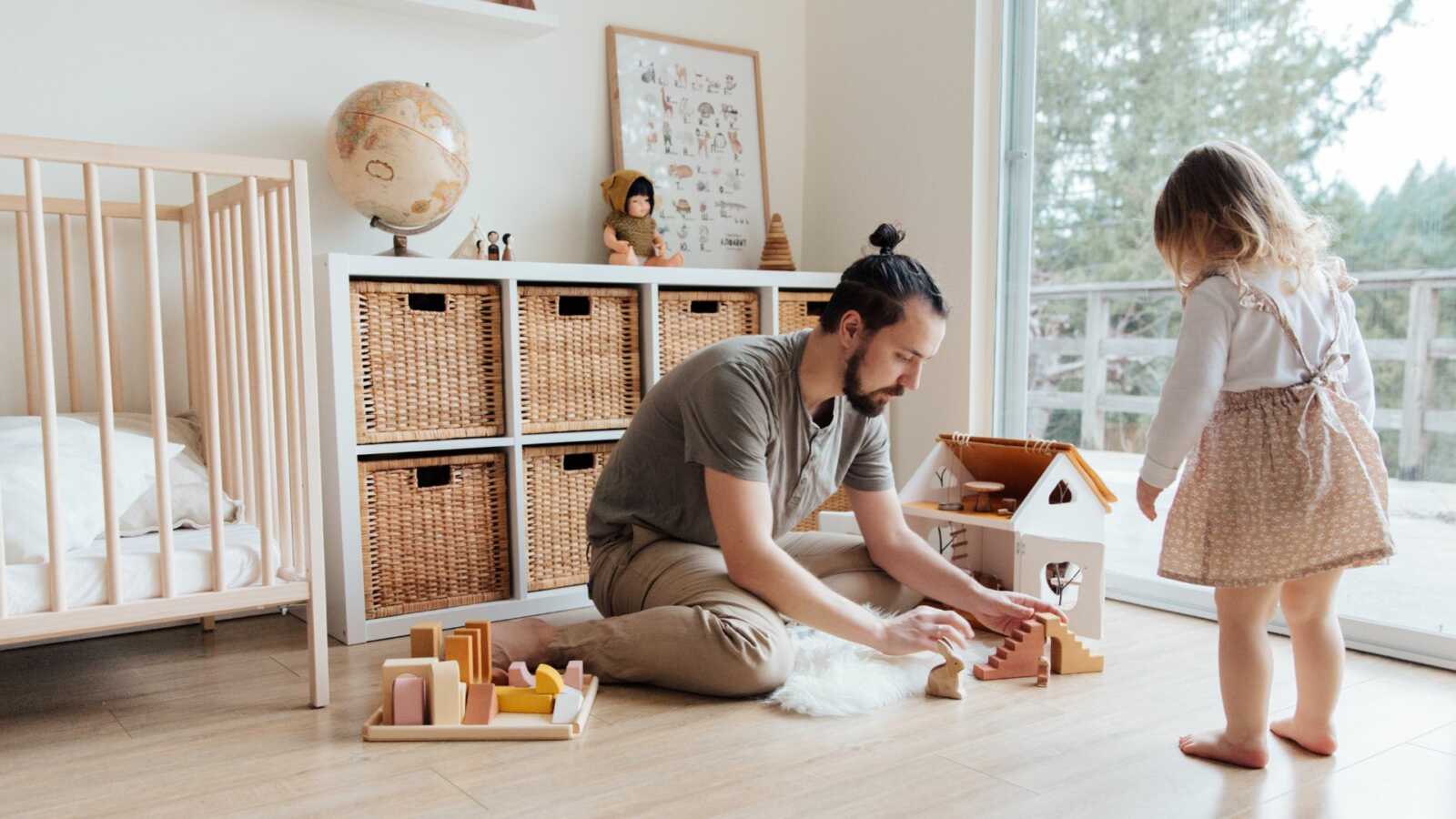 father playing with toddler daughter in bedroom