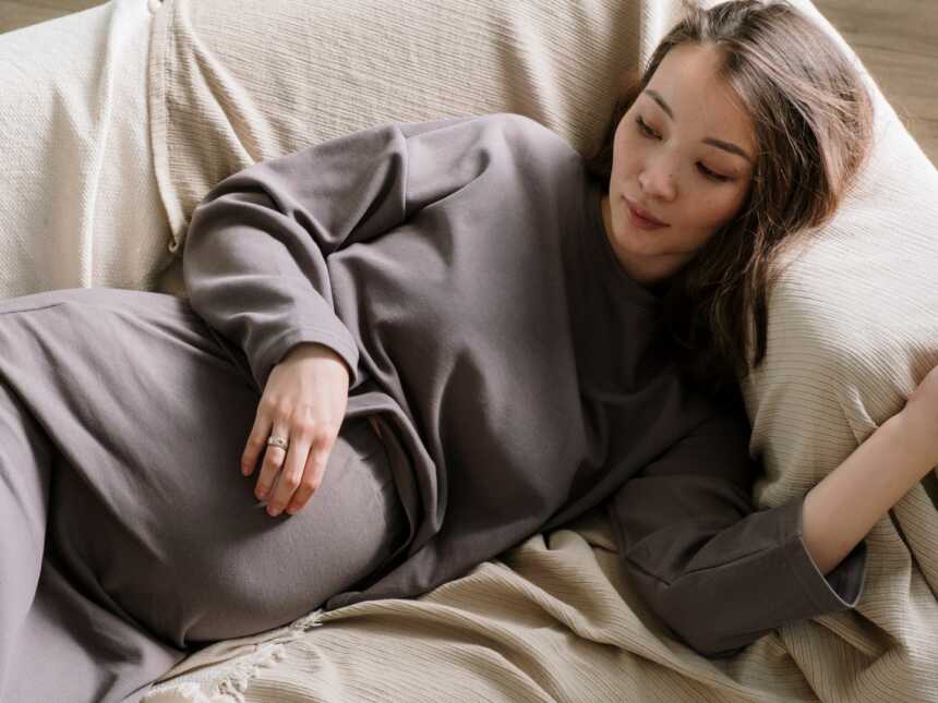 sad pregnant woman lying on couch Photo by cottonbro studio via Pexels