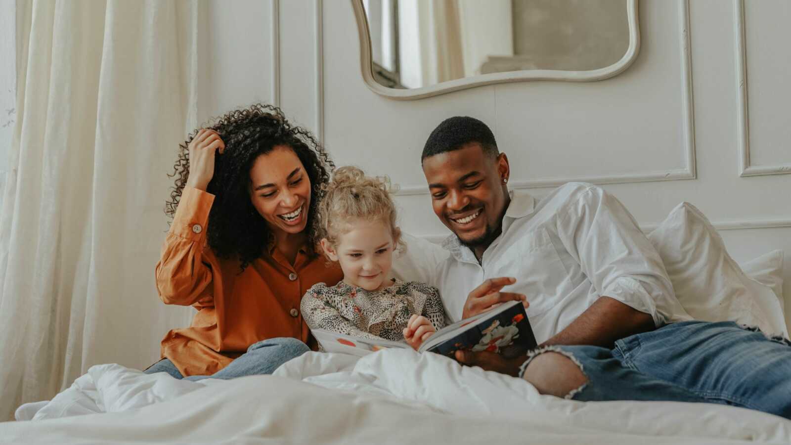 adoptive parents reading in bed with daughter