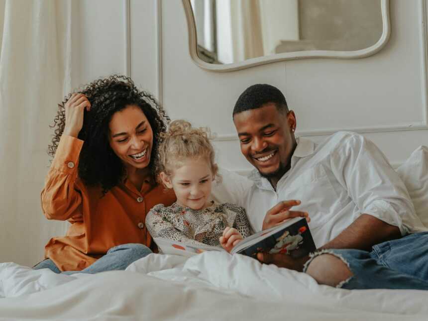 adoptive parents reading in bed with daughter