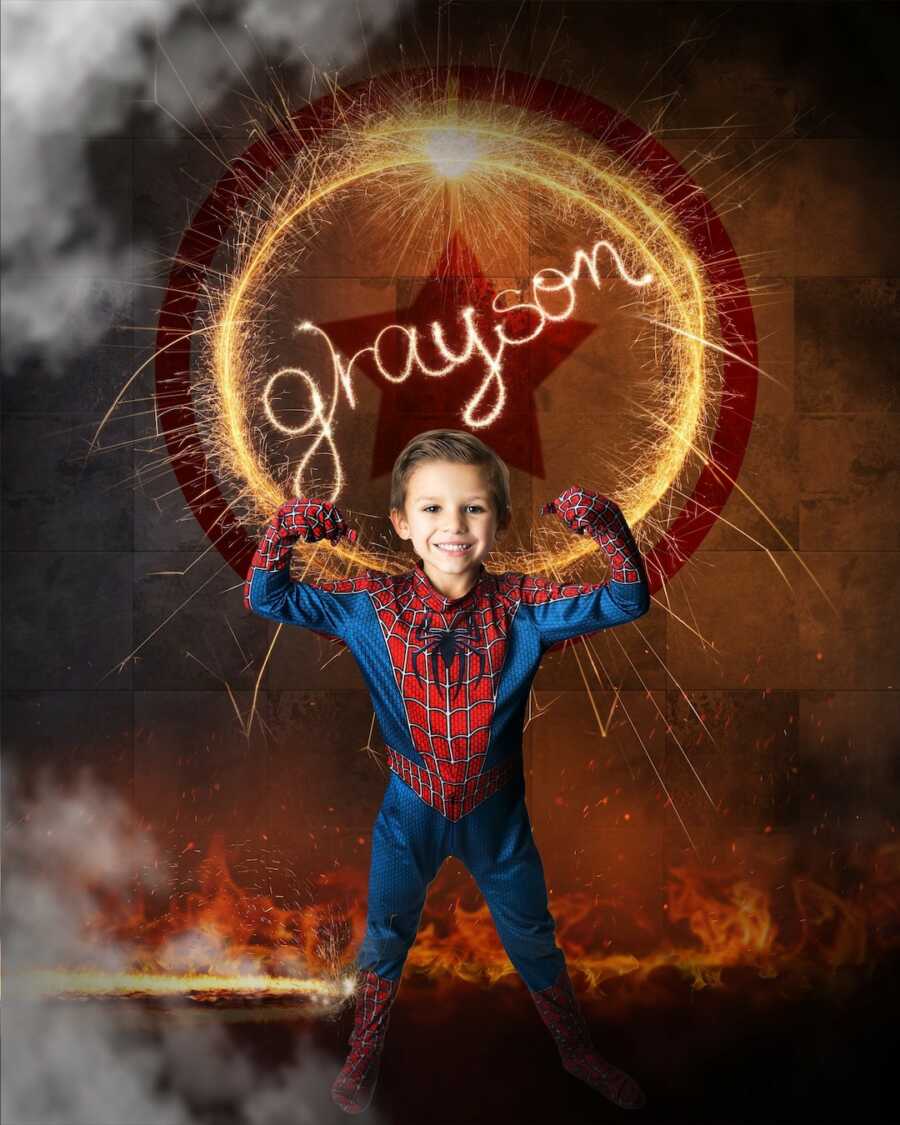 Boy in Spider Man costume flexes in front of his name 