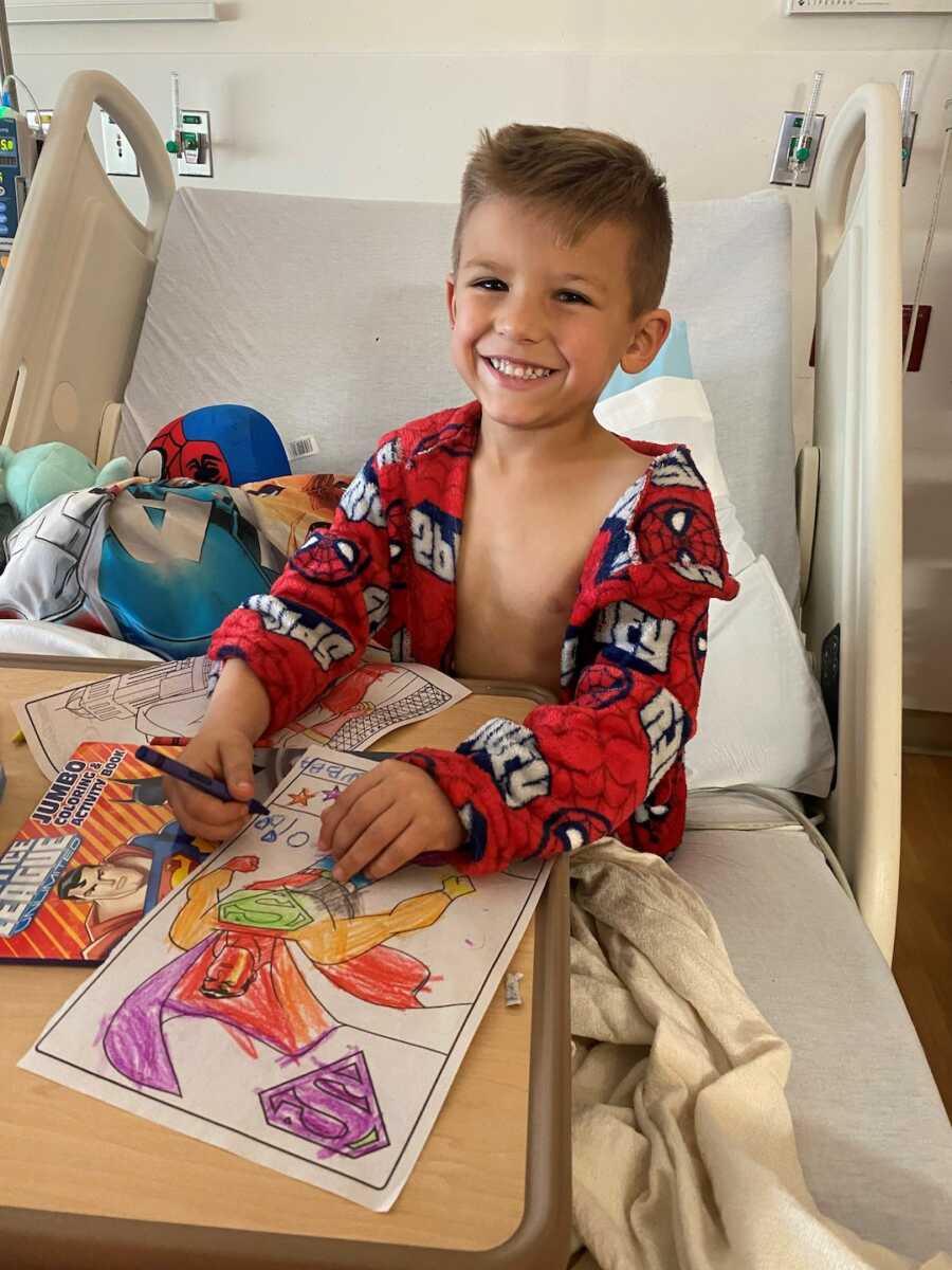 Young boy colors in his hospital bed